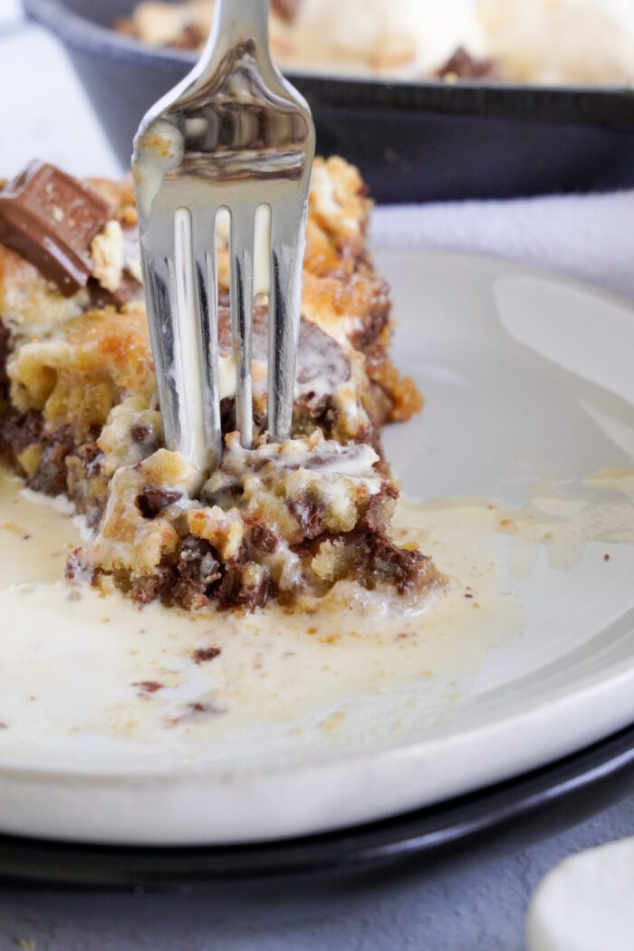 Taking a bite from a slice of S'mores Skillet Cookie