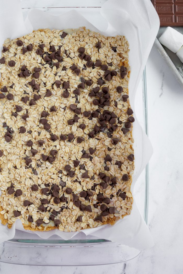 Sweetened condensed milk, oats, and chocolate chips poured on top of graham cracker crust