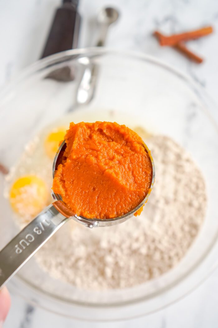 A measuring spoon holding pumpkin puree.