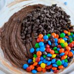 Chocolate chips and M&Ms added to bowl