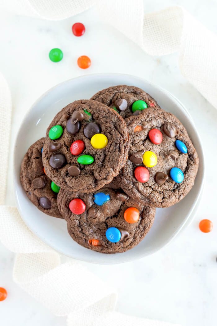 A plate of chocolate cookies with colorful candies.