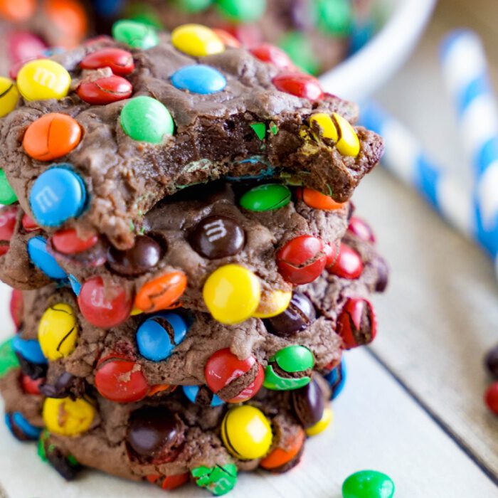 A stack of three chocolate cookies with colorful candies.