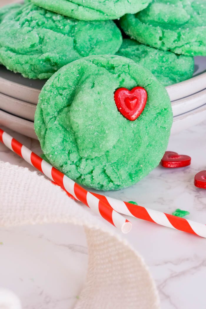 Green sugar cookie with red heart-shaped candy.