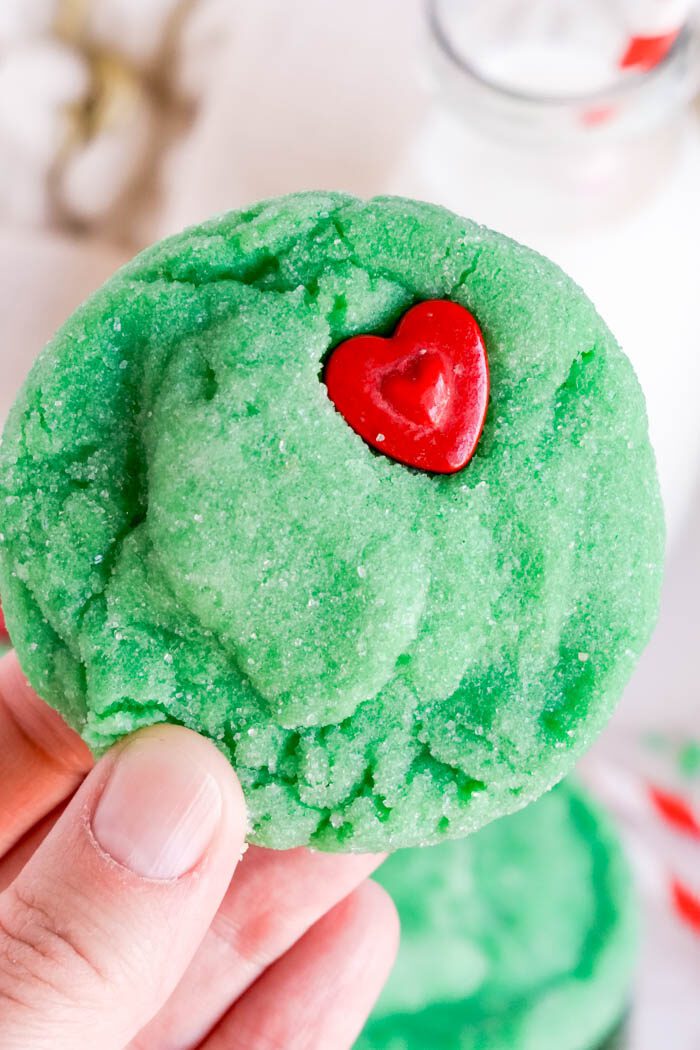 A green sugar cookie with a red heart-shaped candy.