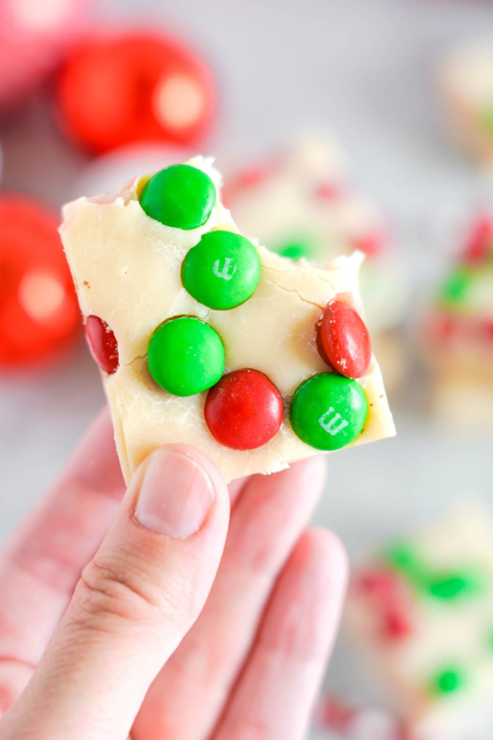 Someone holding a M&M Christmas Fudge squares with a bite taken out