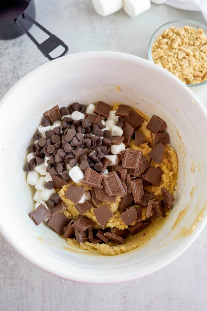 Chocolate chips, marshmallows, and Hershey bar added to mixing bowl