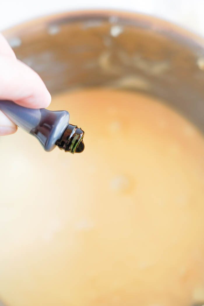 A hand adding drops of food coloring to a pot.