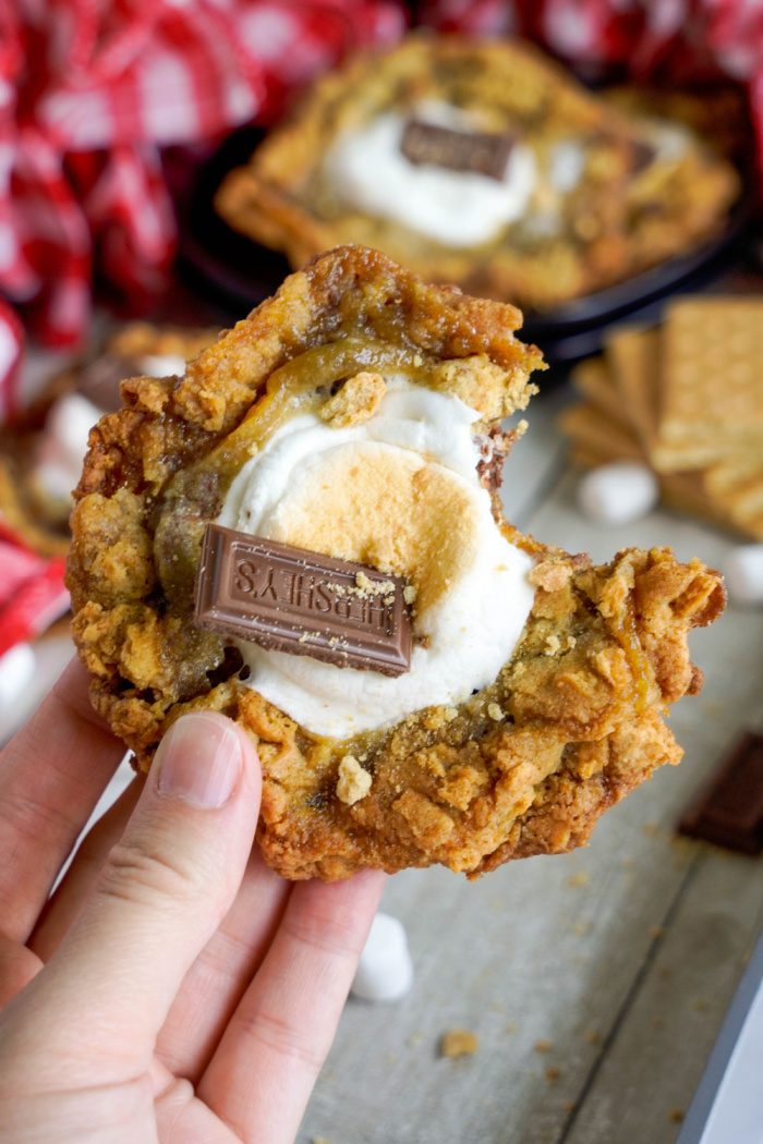 Someone holding a S'mores Cookie with a bite taken out