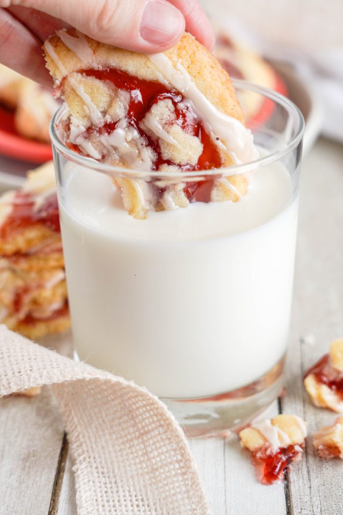 Someone dunking a Cherry Pie Cookie in a glass of milk