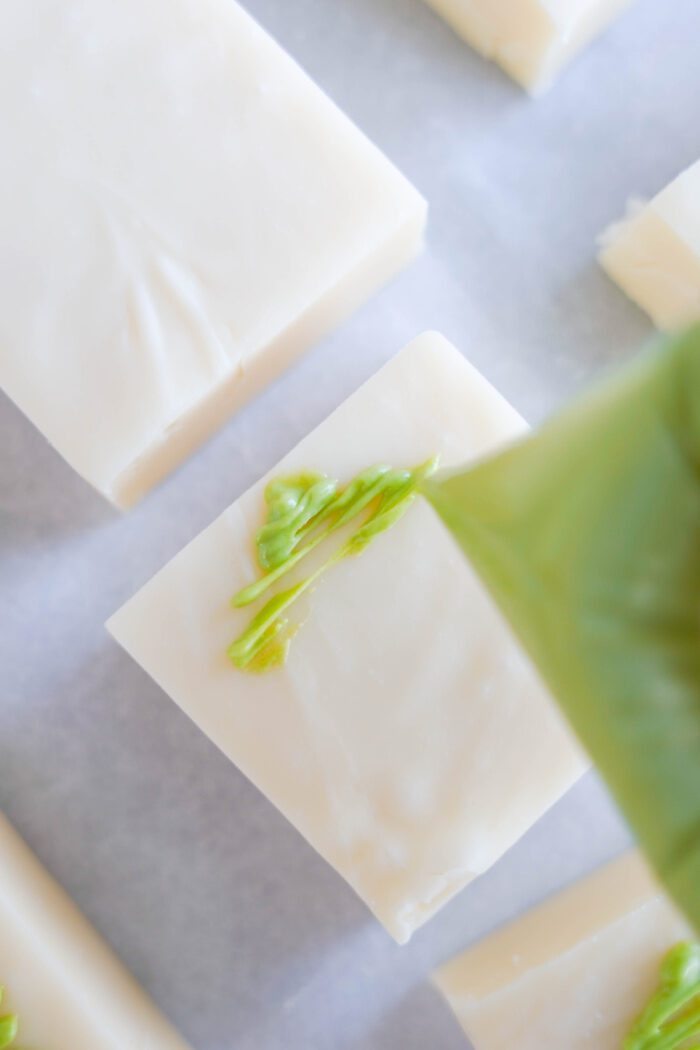 Drizzling green almond bark onto fudge squares