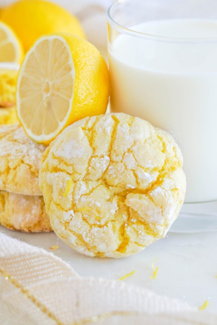 Lemon Crinkle Cookie propped up against a glass of milk