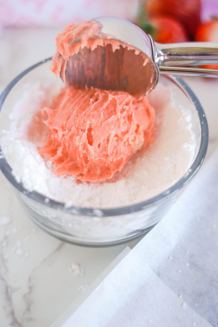 Rolling cookie dough ball in powdered sugar