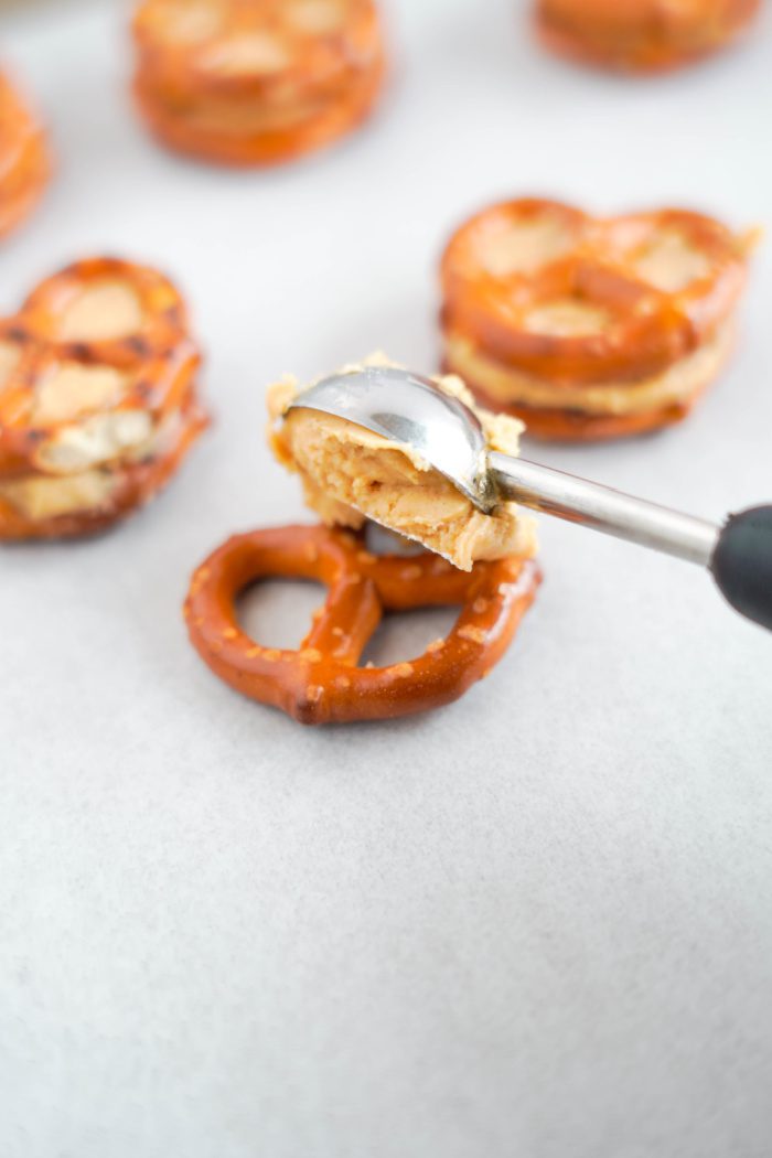 Scooping peanut butter mixture onto pretzels