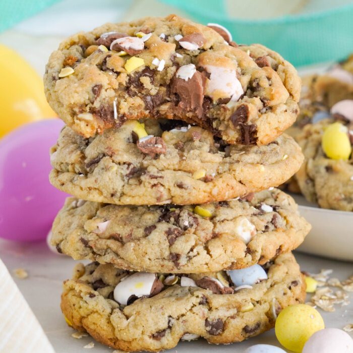 A stack of four chocolate chip cookies with pastel-colored candy pieces.