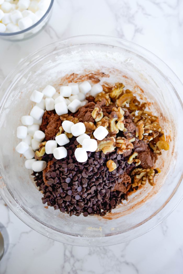 Chocolate chips, walnuts, and marshmallows added to bowl