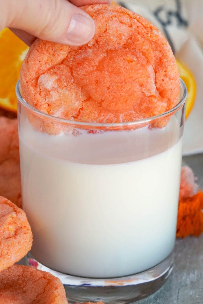 Someone dunking a Creamsicle Orange Cookie in glass of milk
