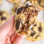 Someone holding a Oreo Chocolate Chip cookie broken in half