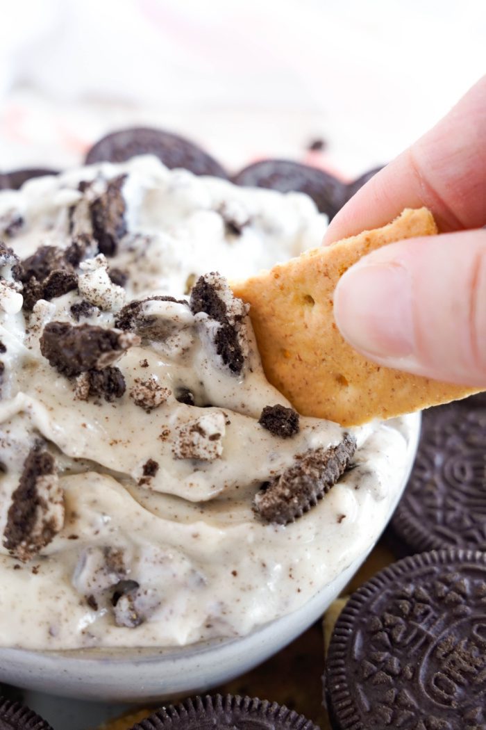Easy Oreo Dip with someone dipping graham cracker into dip