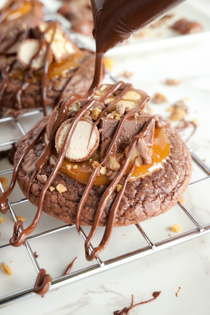 Candy Bar Brownie Cookies being drizzled with chocolate