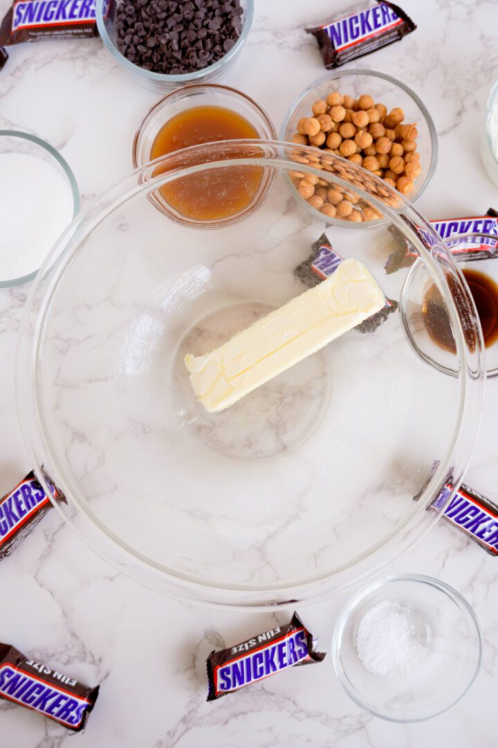 Snickers Dip adding butter to bowl