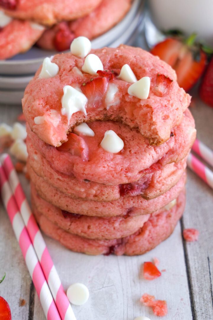 Strawberry White Chocolate Chip Cookies stacked with a bite taken out of the top one
