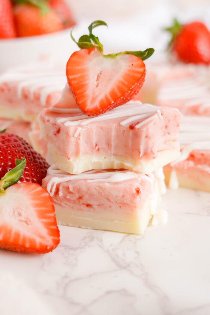 Strawberry Swirl Fudge stacked with sliced strawberries