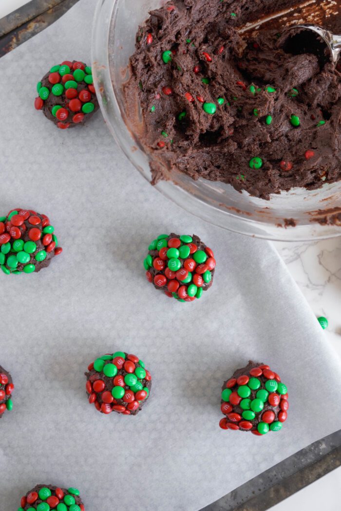 Brownie M&M Christmas Cookie dough balls placed on baking sheet