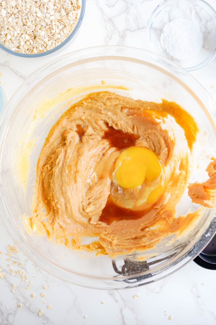 Peanut Butter Oatmeal Cookie batter adding egg and vanilla