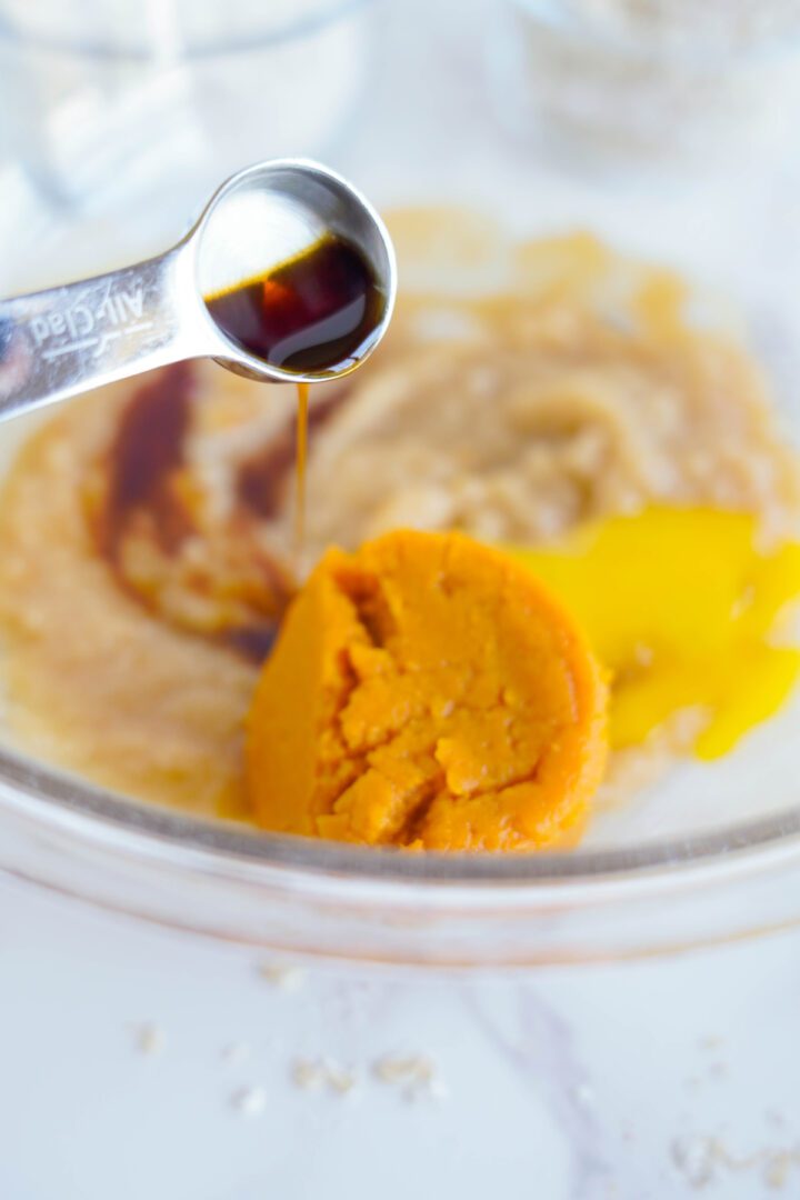 Pumpkin Oatmeal Cookie batter adding vanilla, pumpkin puree, and egg yoke