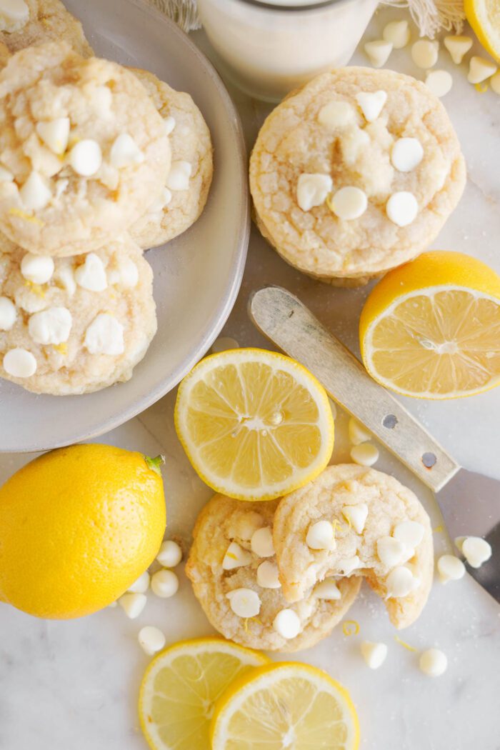 Freshly baked Lemon White Chocolate Chip Cookies served with sliced lemons and a glass of milk.