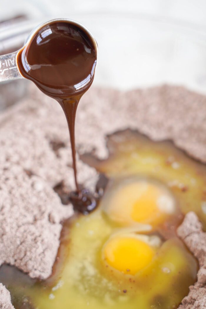 A chocolate sauce is being poured over eggs in a bowl for Easy Brownie Cookies for Easter.