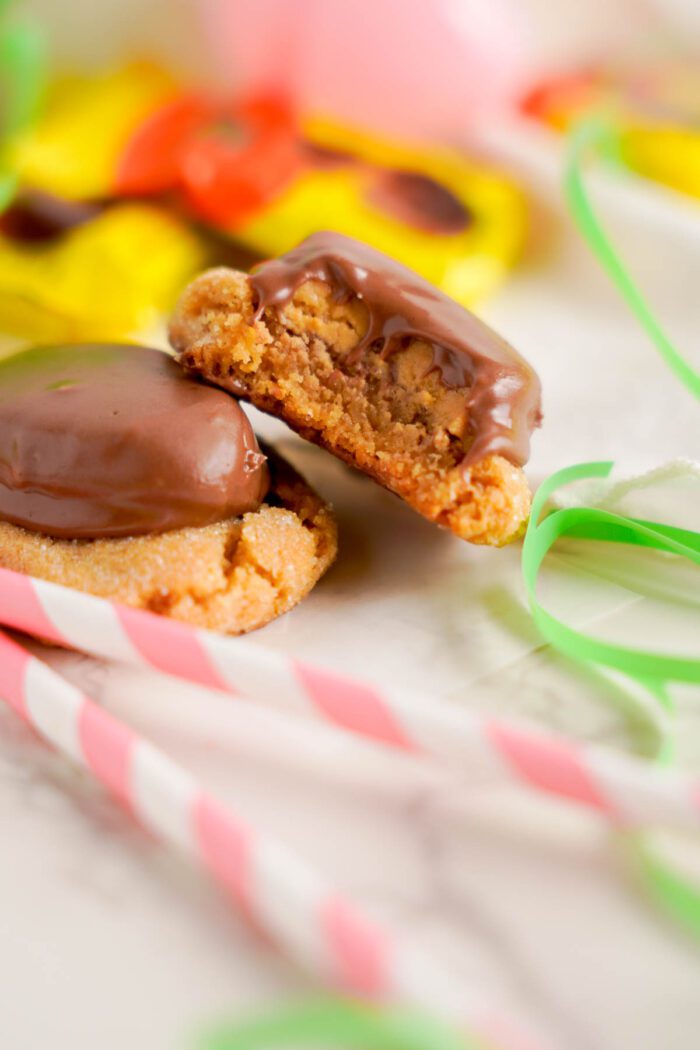 A Reese's Egg peanut butter biscuit with a bite taken out, surrounded by colorful ribbons.