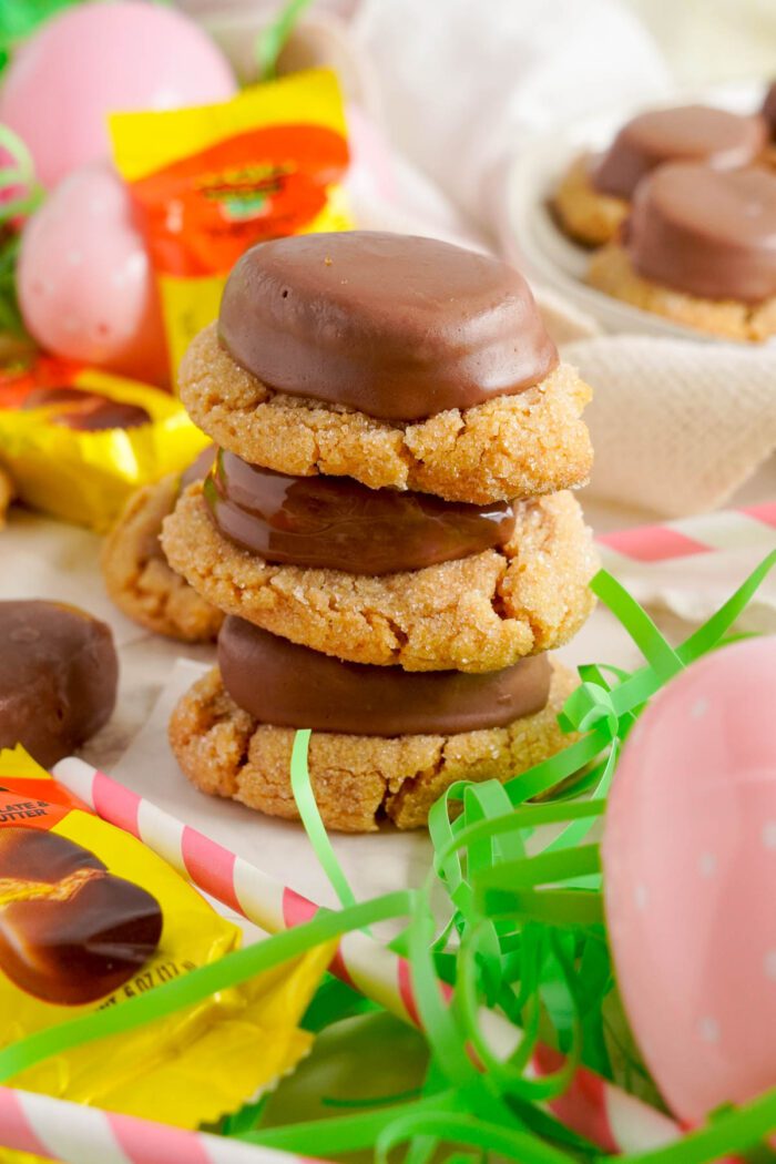 A stack of Reese's Egg Peanut Butter Cookies surrounded by Easter candy and decorations.