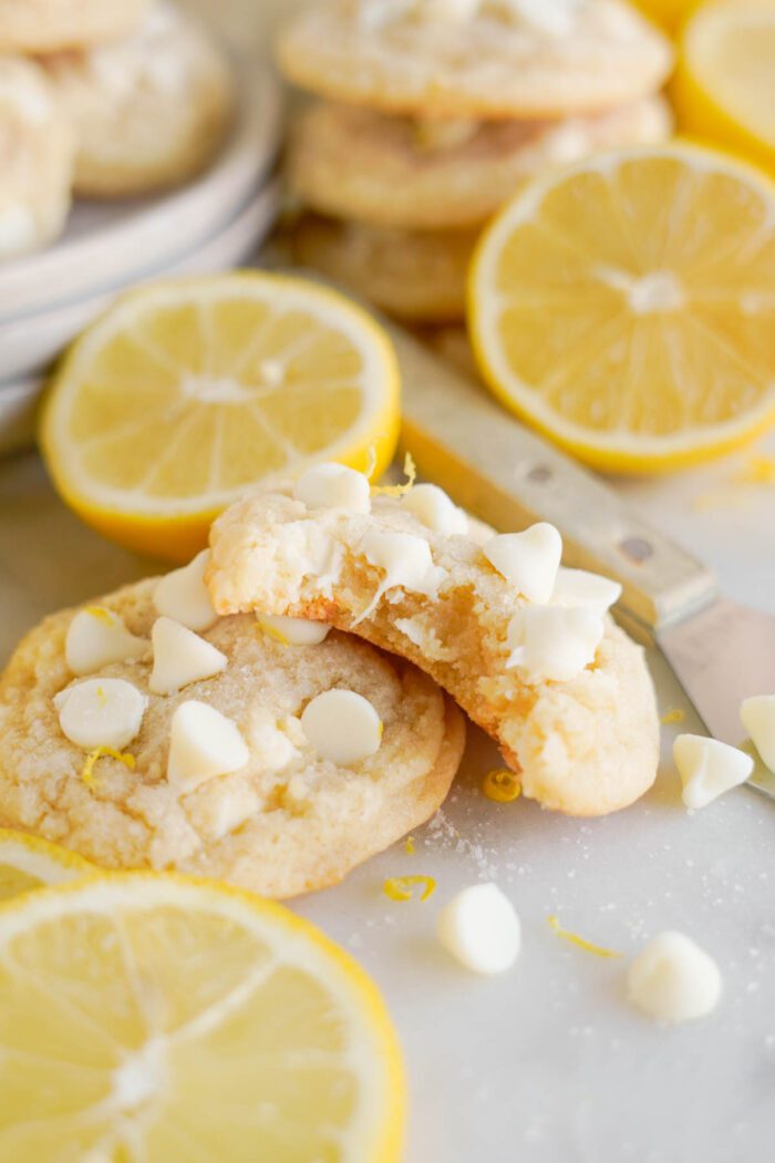 Freshly baked Lemon White Chocolate Chip Cookies, accompanied by lemon slices.