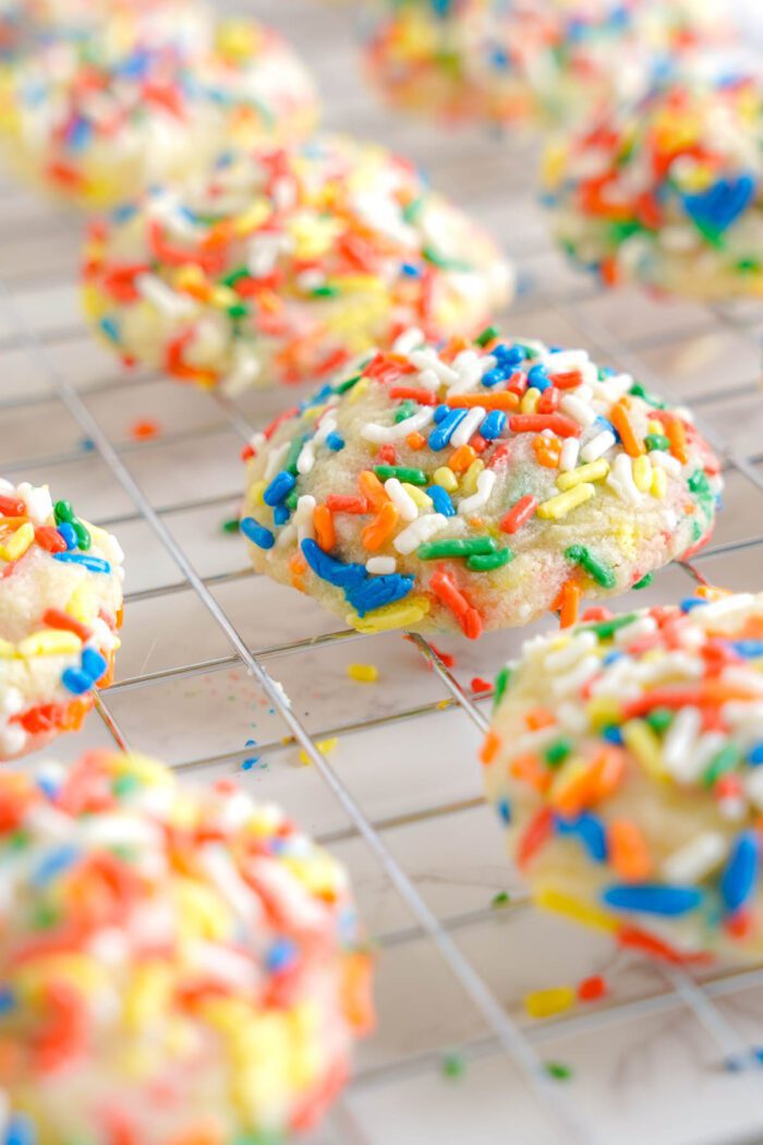 Freshly baked sugar cookies with colorful sprinkles cooling on a wire rack.