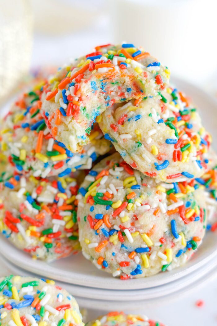 A stack of sprinkle-covered cookies on a plate.