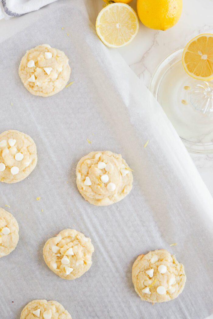 Freshly baked Lemon White Chocolate Chip Cookies on parchment paper.