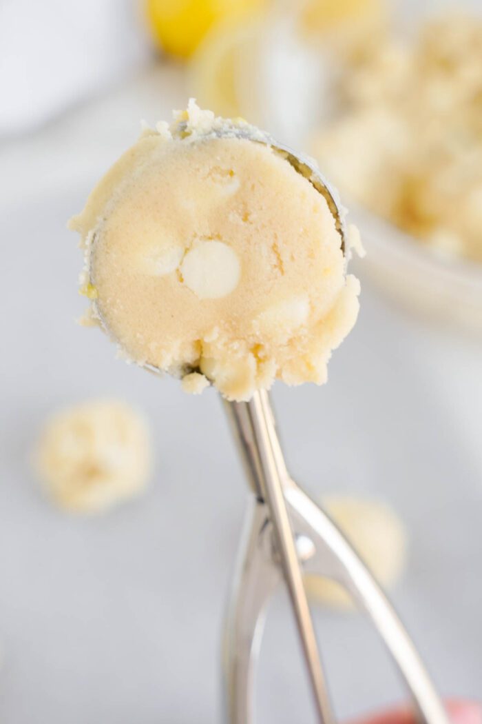 Lemon White Chocolate Chip Cookie dough in a scoop with more dough in the background.