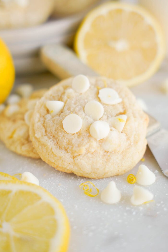 A Lemon White Chocolate Chip Cookie garnished with lemon zest, accompanied by fresh lemon slices.