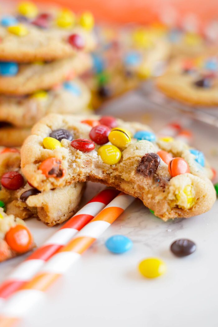 Colorful candy-coated chocolates scattered around and embedded in freshly baked peanut butter cookies.