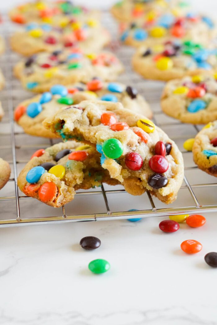 Freshly baked Peanut Butter M&M cookies cooling on a wire rack.