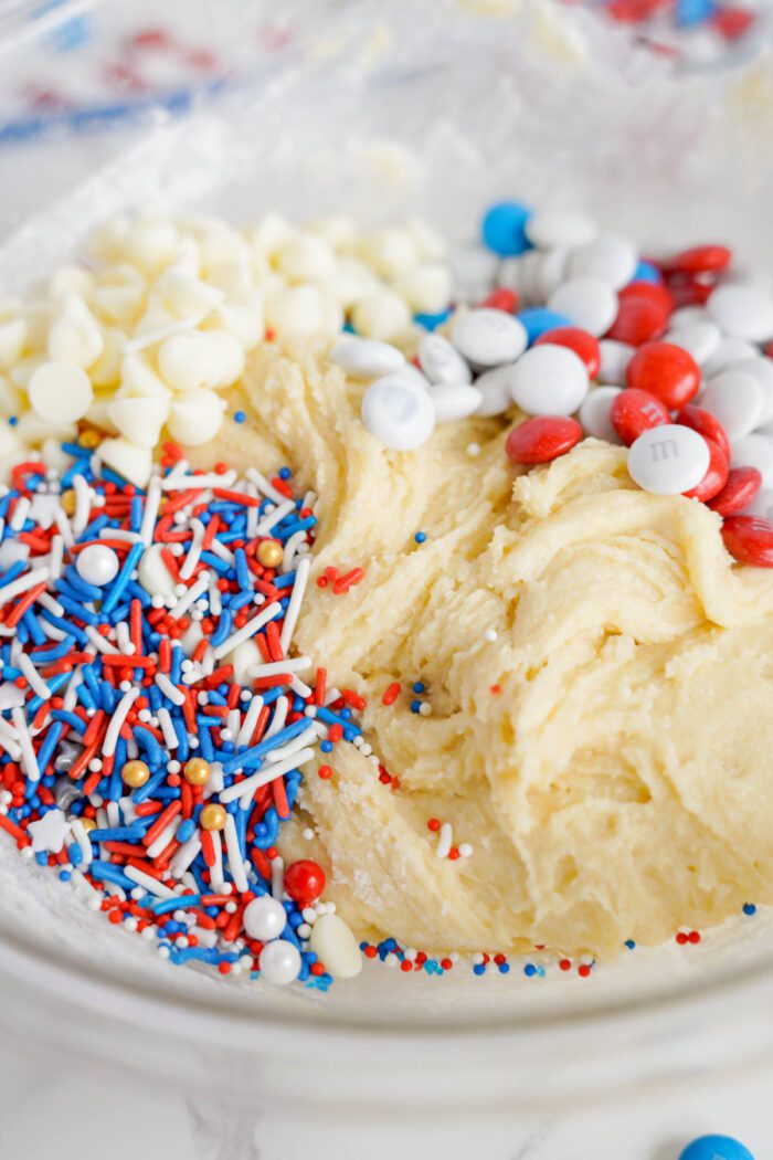 Cookie dough in a glass bowl with red, white, and blue sprinkles and candy-coated chocolates mixed in, perfect for making Easy 4th of July Cake Mix Cookies.