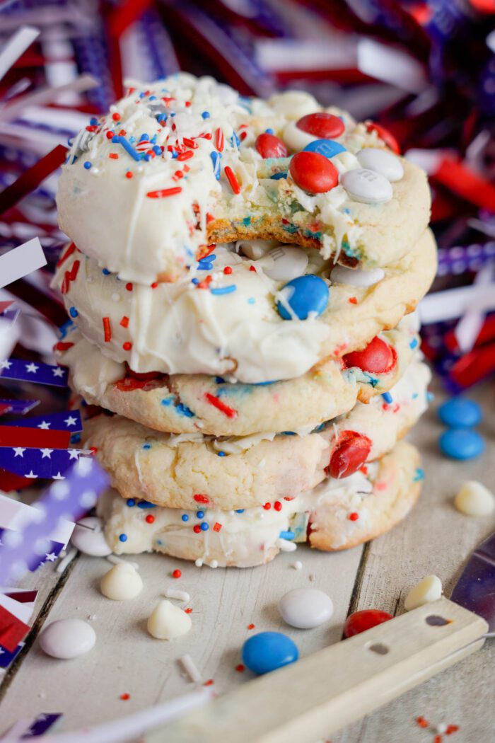 Stack of red, white, and blue sprinkle Easy 4th of July Cake Mix Cookies with vanilla ice cream, surrounded by patriotic decorations.