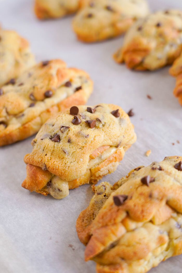 Freshly baked chocolate chip cookie croissants on parchment paper.