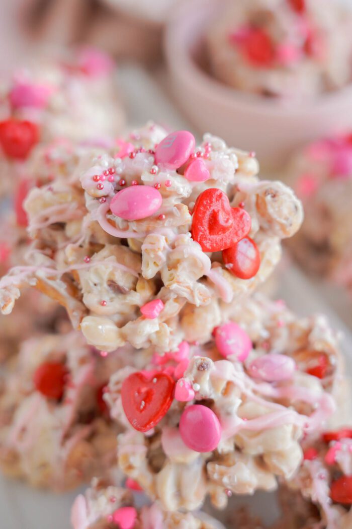 Close-up of a stack of valentine's day crockpot candy adorned with pink and red candies and heart-shaped sprinkles.