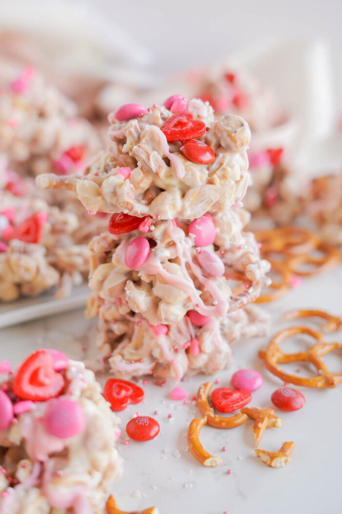 Clusters of Valentine's Day pretzel treats coated in white chocolate and sprinkled with pink and red candies.