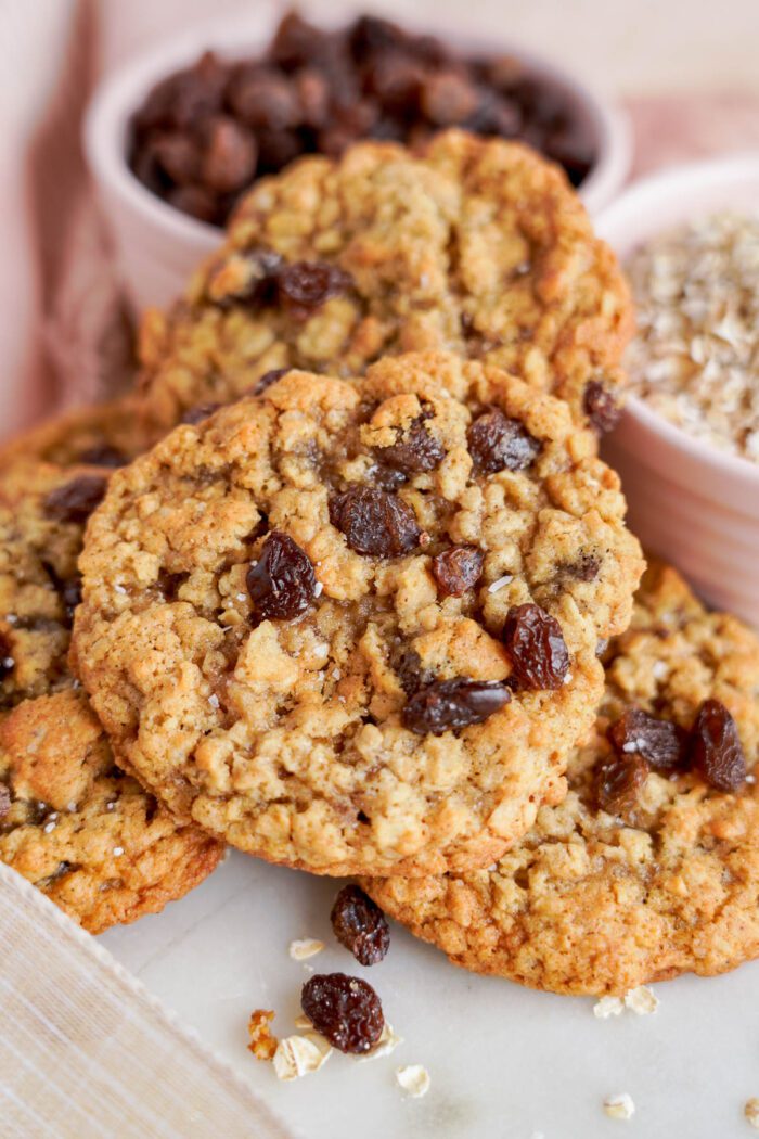 Close-up of the best oatmeal raisin cookies with visible oats and raisins, accompanied by ingredients in the background.