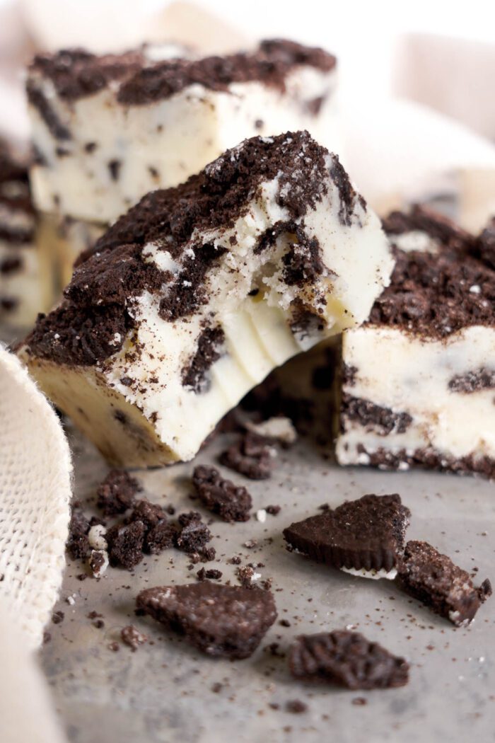 Stack of Oreo fudge pieces with crumbled cookies on a light background.