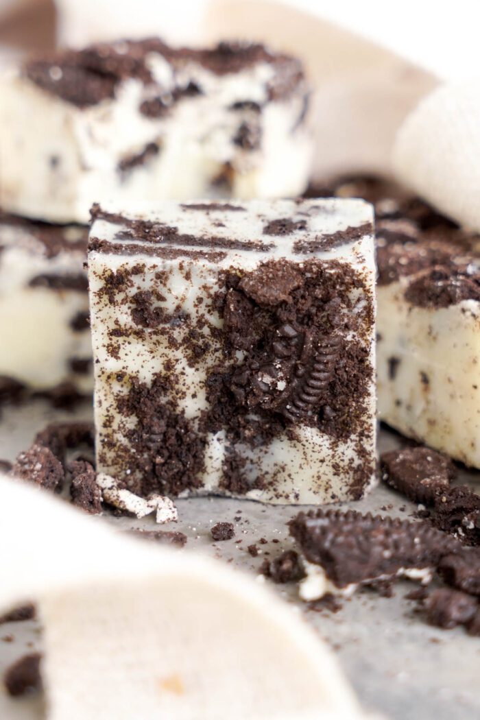 Pieces of Oreo fudge surrounded by crumbled cookies.