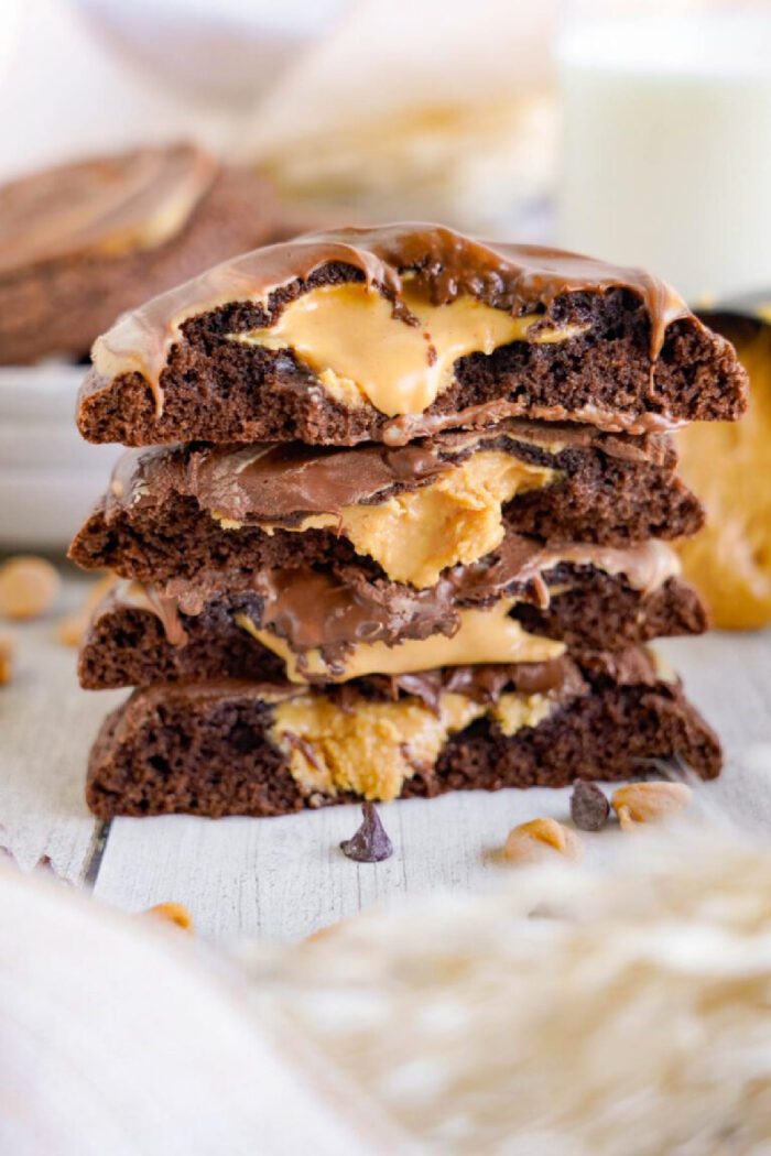 A stack of chocolate peanut butter brownie cookies with gooey peanut butter layers, displayed on a white surface.